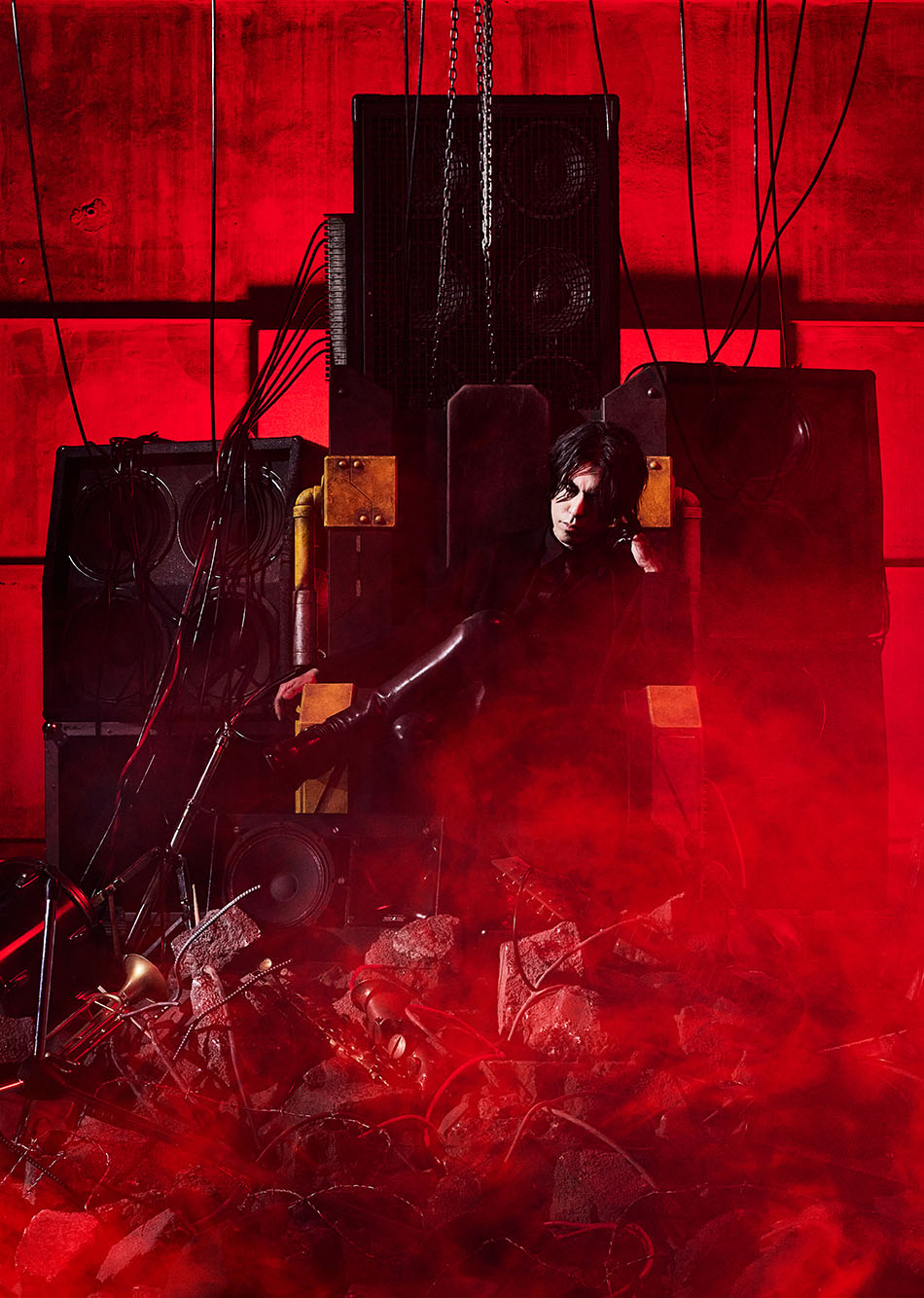 HAZUKI solo pic. HAZUKI is sitting on a throne made of guitar amps.