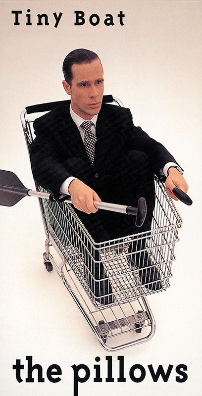 the pillows Tiny Board single cover art. It features a man in a business suit sitting in a shopping trolly cart.